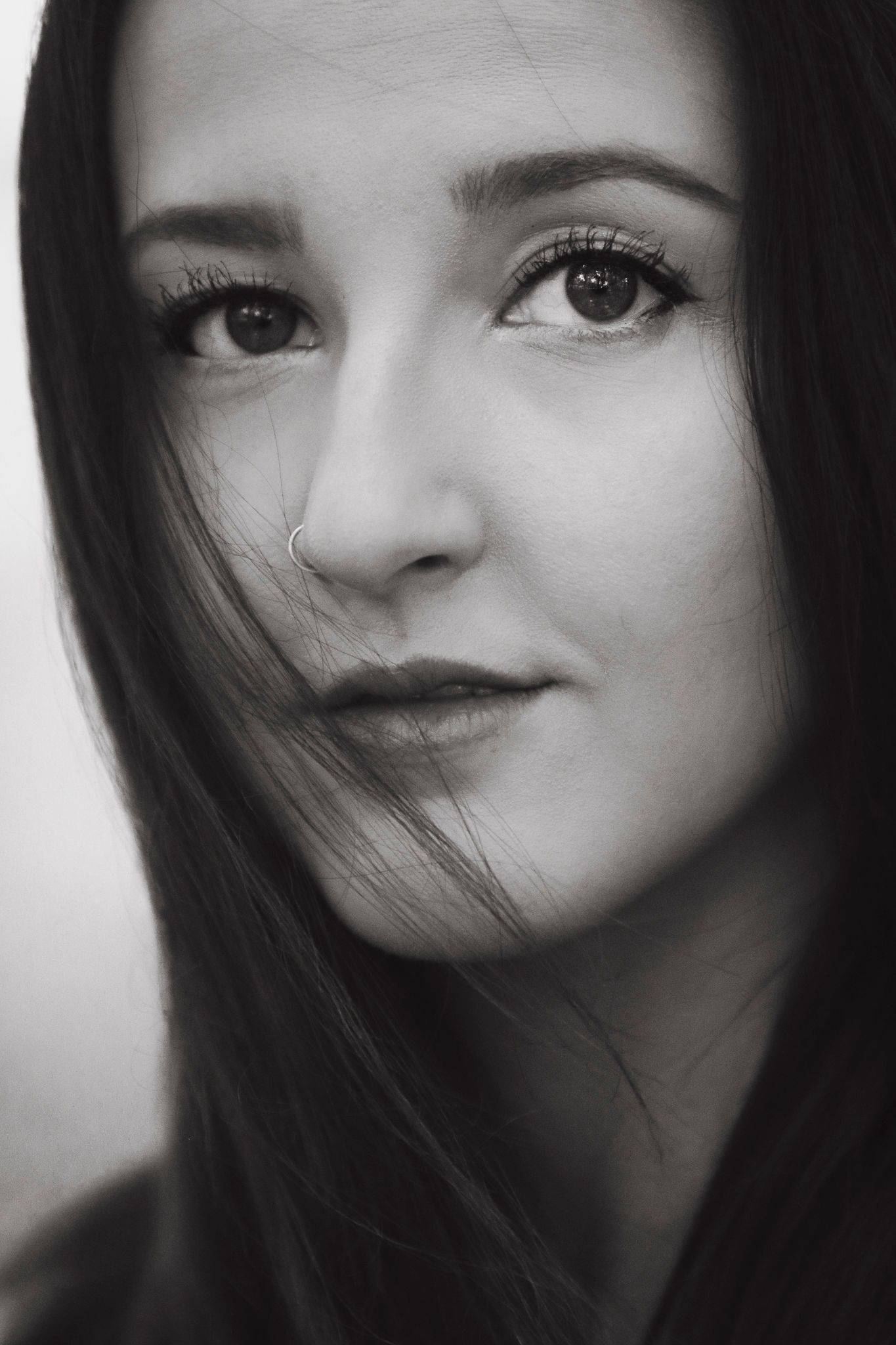 Black and white portrait with soft lighting highlighting expressive eyes and dark hair.