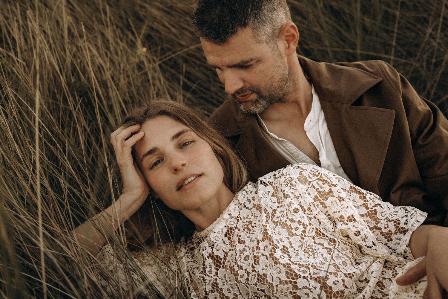 A couple in a romantic embrace wearing brown and white outfits pose together in a natural outdoor setting. Javea photographer