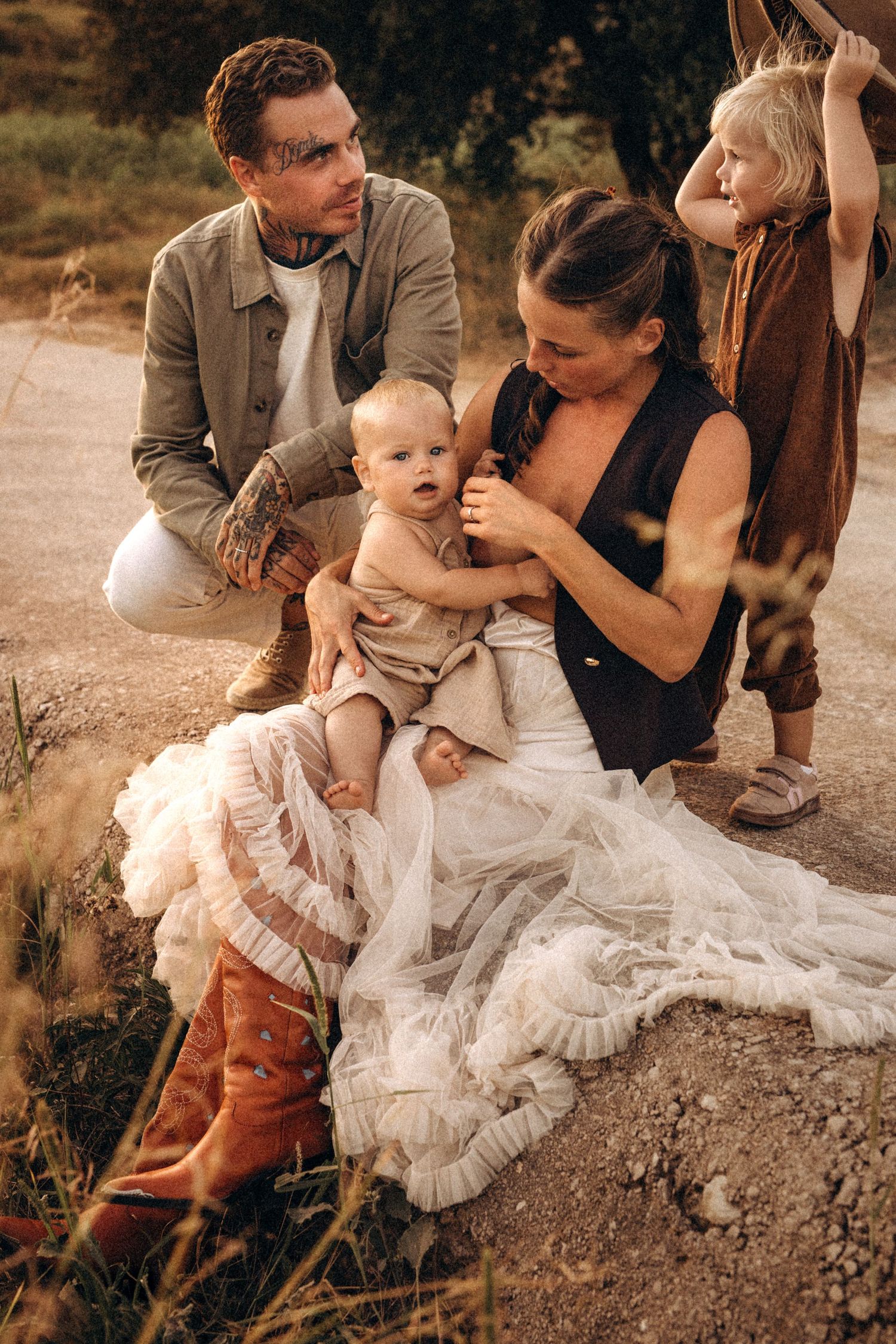 Family sitting together outdoors in warm sunlight wearing neutral colors and flowing white dress. Javea photographer