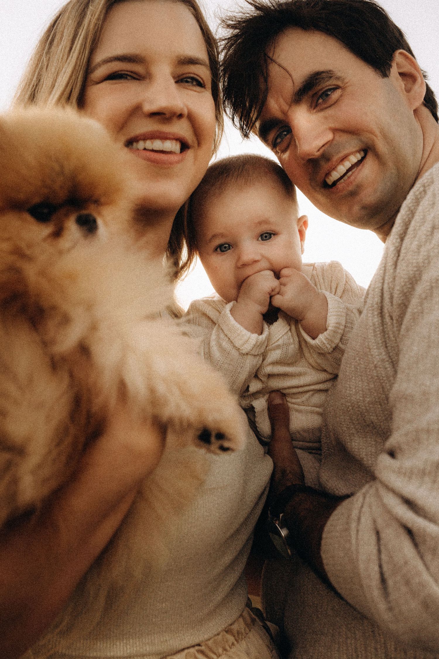A series of warm-toned intimate family photos showing tender moments between parents and baby in matching beige sweaters. Javea photographer