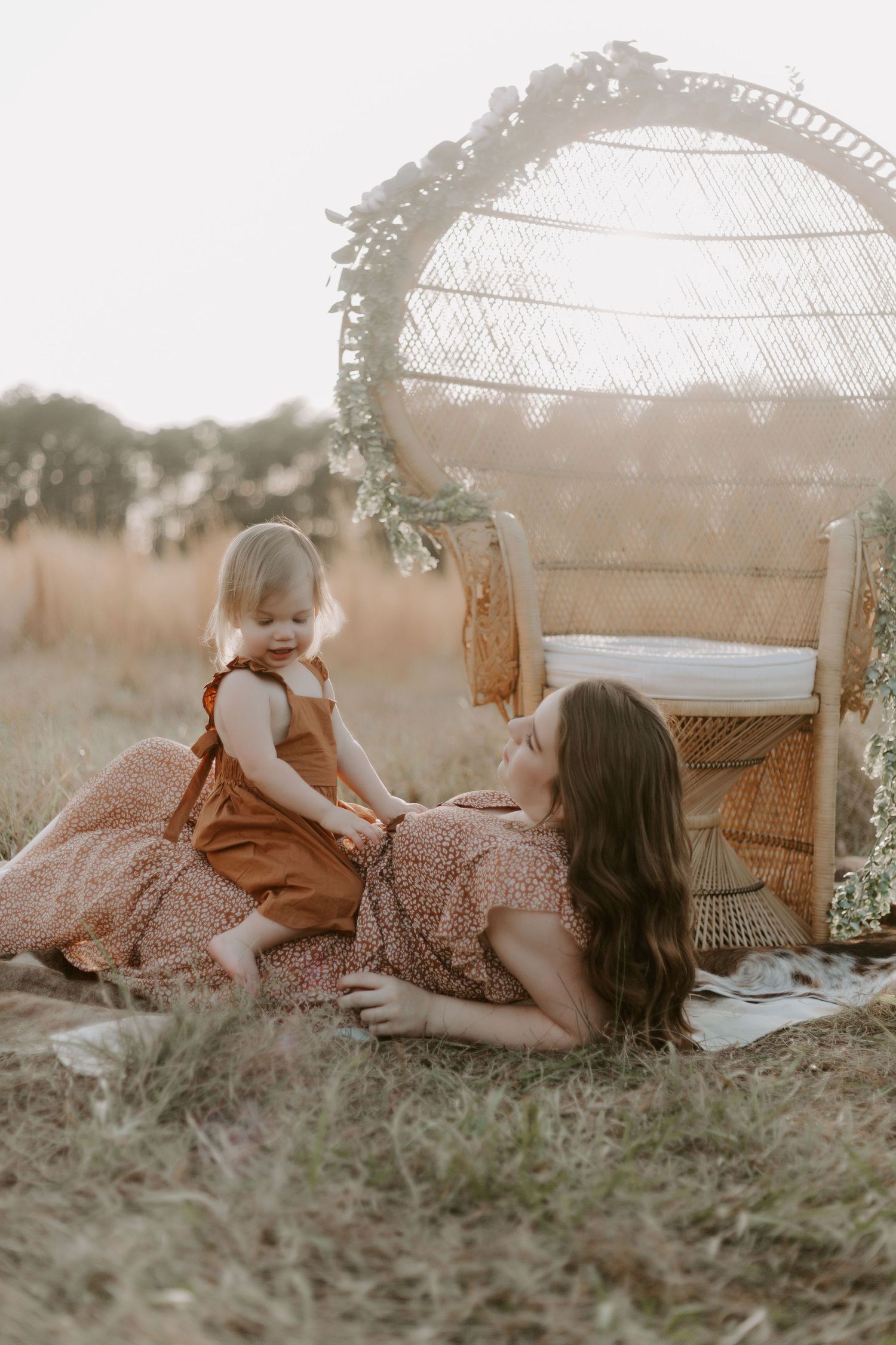 Mother and daughter photo session, they are enjoying their time sitting in a field at sunset together