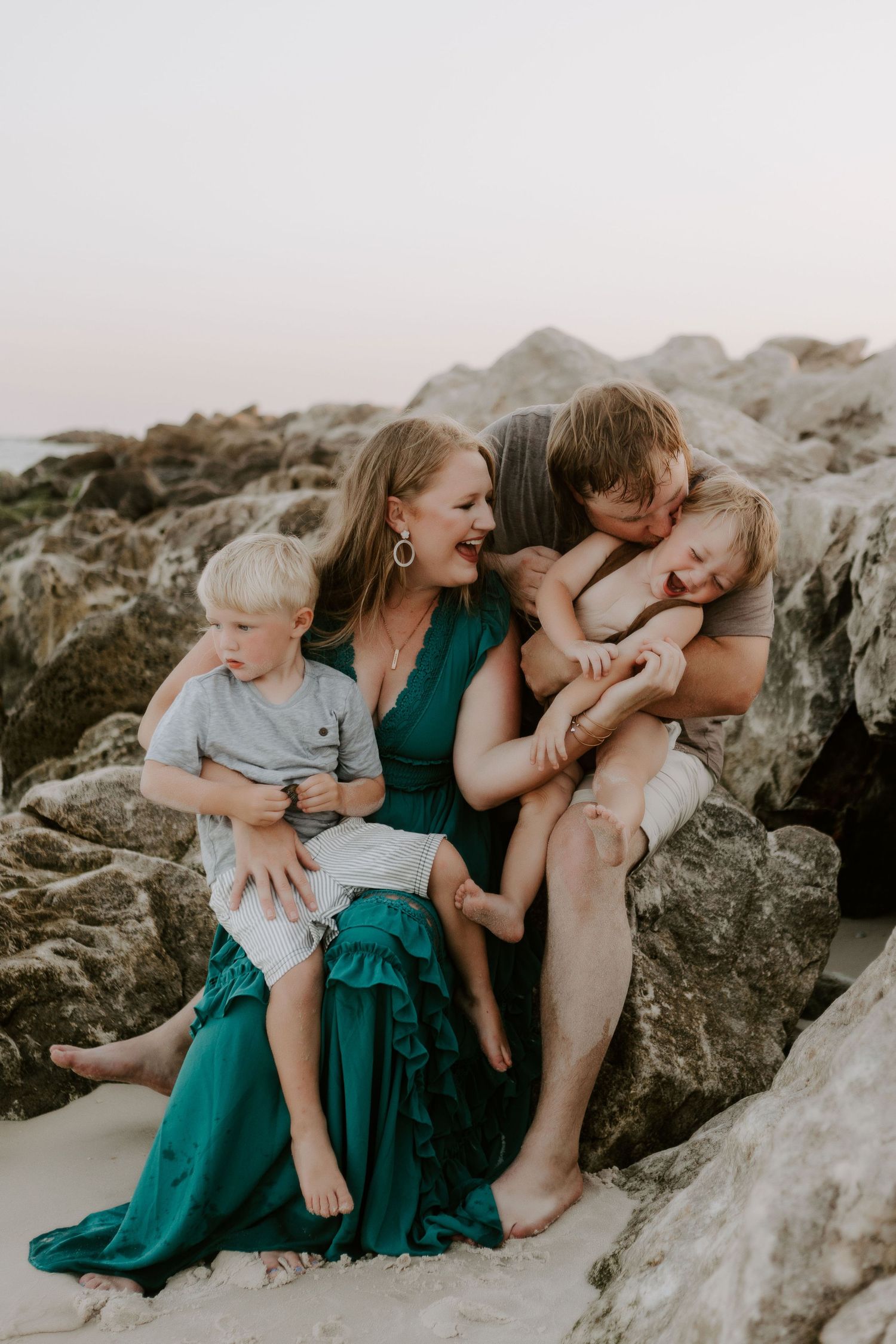 Family photo of a family laughing and kissing on the beach in Pensacola, Florida