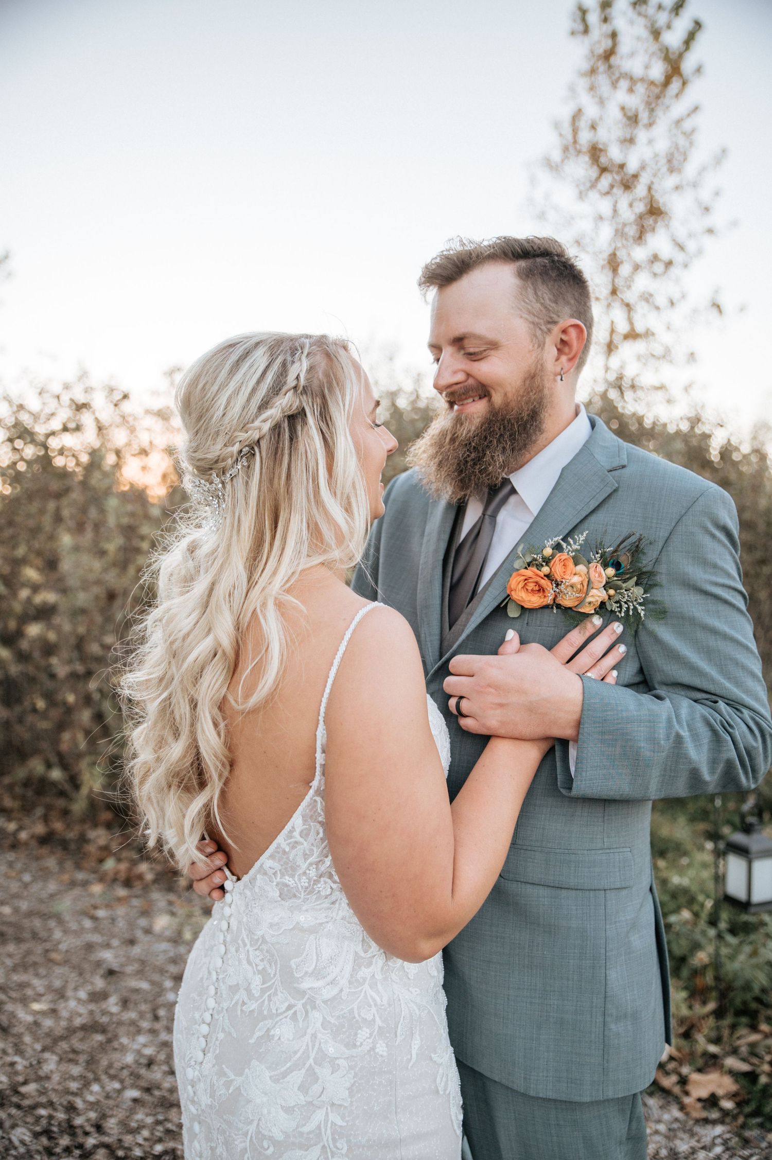 A romantic moment between a couple in wedding attire outdoors during sunset with orange floral accents at Kruze Plaza, in Auburn, Indiana.