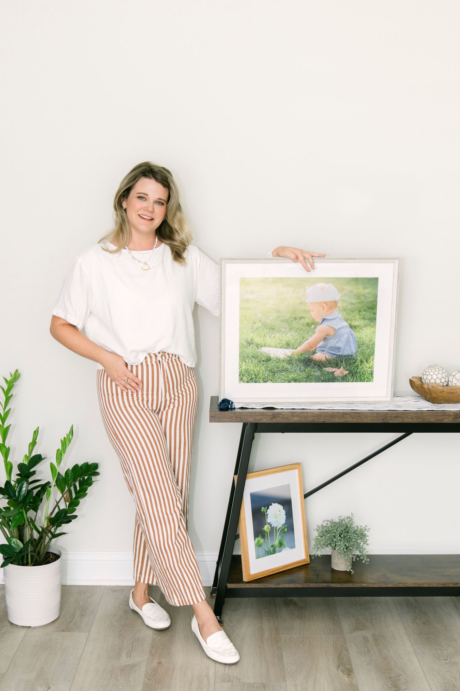 Best of St Simons Island Photographer Lindy Rebro standing in front of a custom framed portrait she took for an heirloom client.