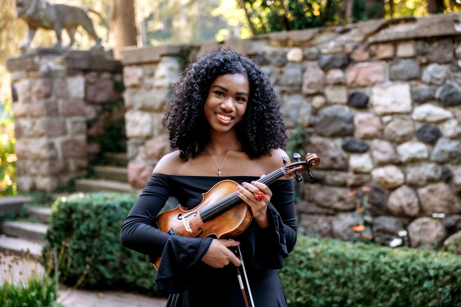 Senior girl poses with violin during her senior pictures at Cranbook House and Gardens. Metro Detroit Senior Pictures