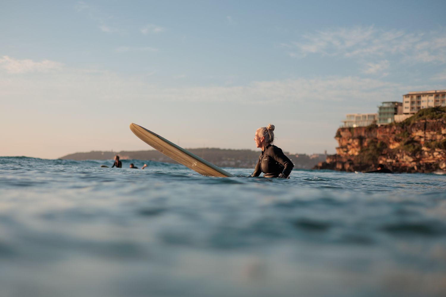 Surfer sitting on a longboard waiting for a wave at Freshwater Beach