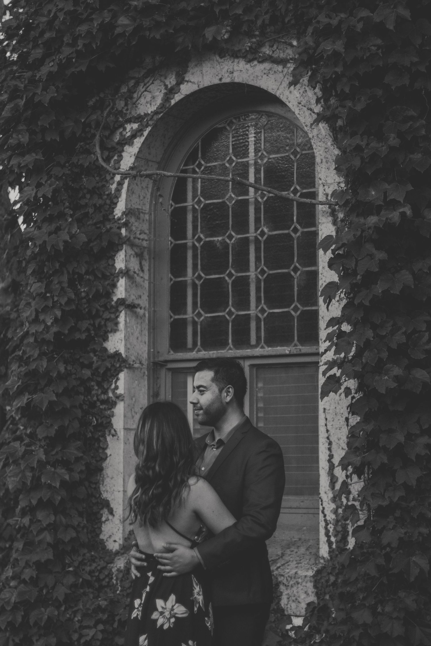 Moody, grainy black and white photo of a couple embracing softly, unposed and honest.