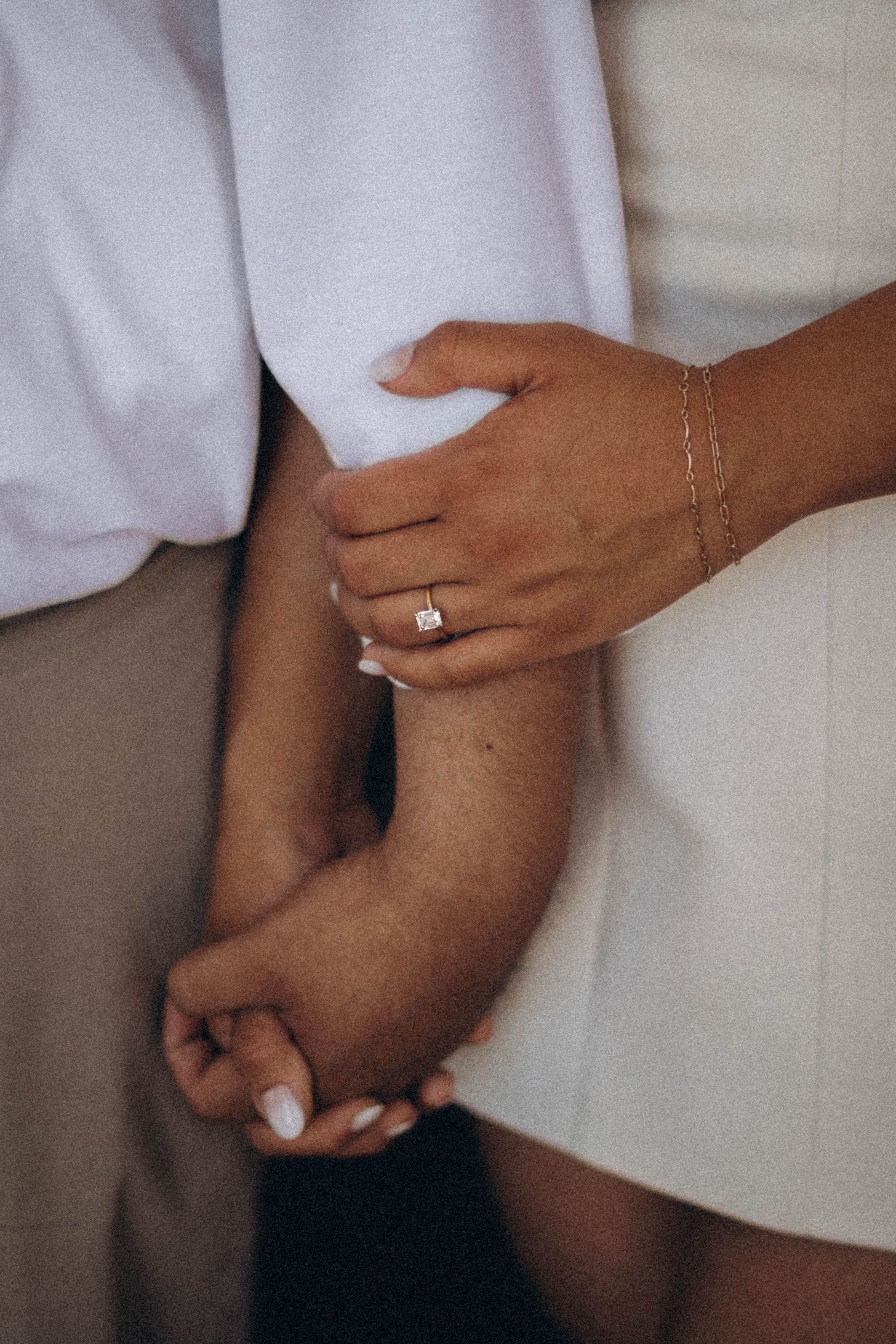 Grainy, warm colored image of hands intertwined, reflecting quiet connection and unposed love.