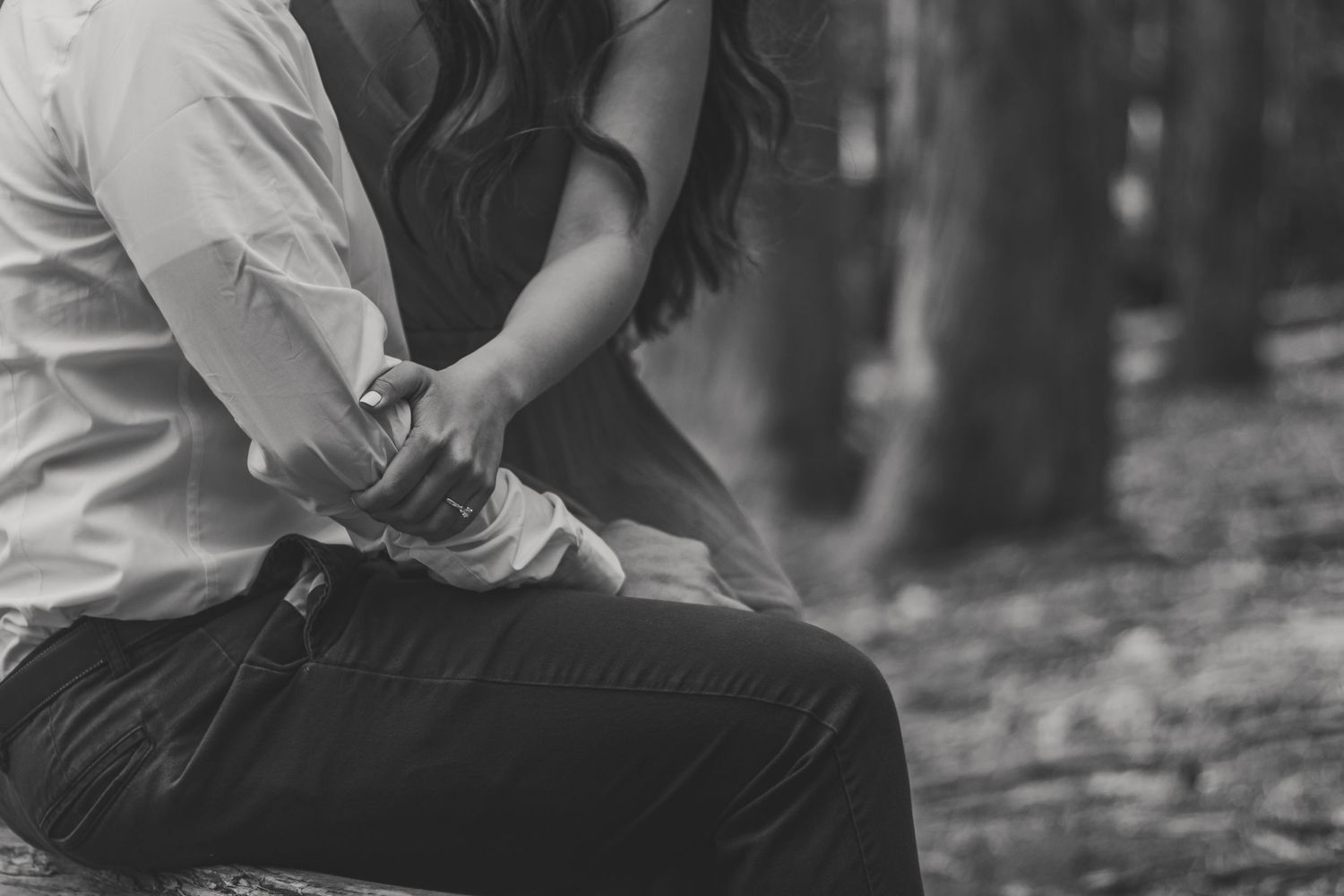 Soft, black and white photo of a couple holding hands, capturing an unposed, quiet moment.