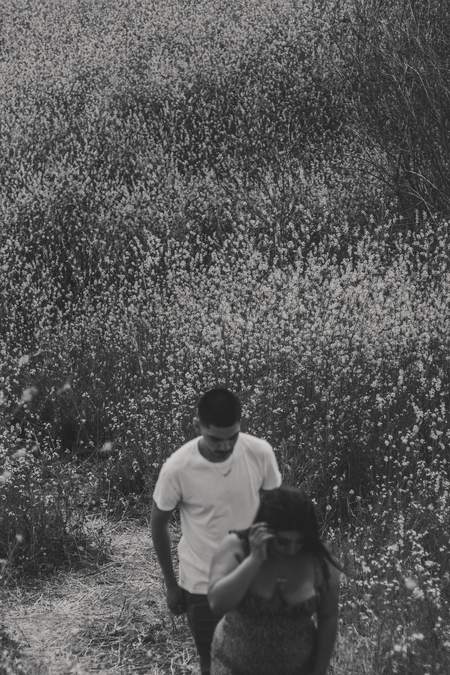 Black and white image of a couple walking, grain creating an artful candid moment