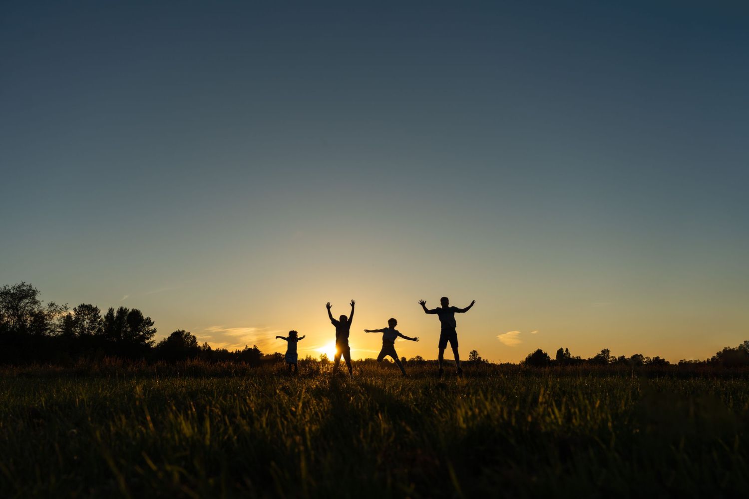 Kids silhouettes jumping at sunset.