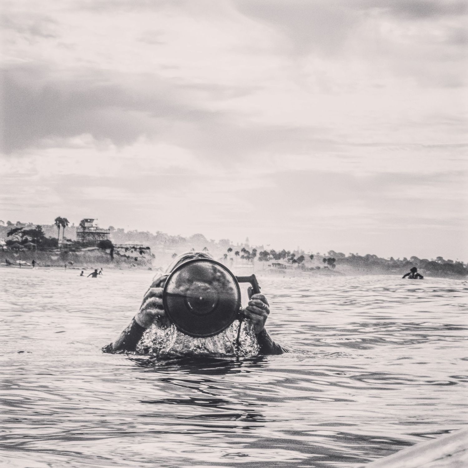 A sequence of black and white photos showing a surfer duck diving under waves in the ocean.