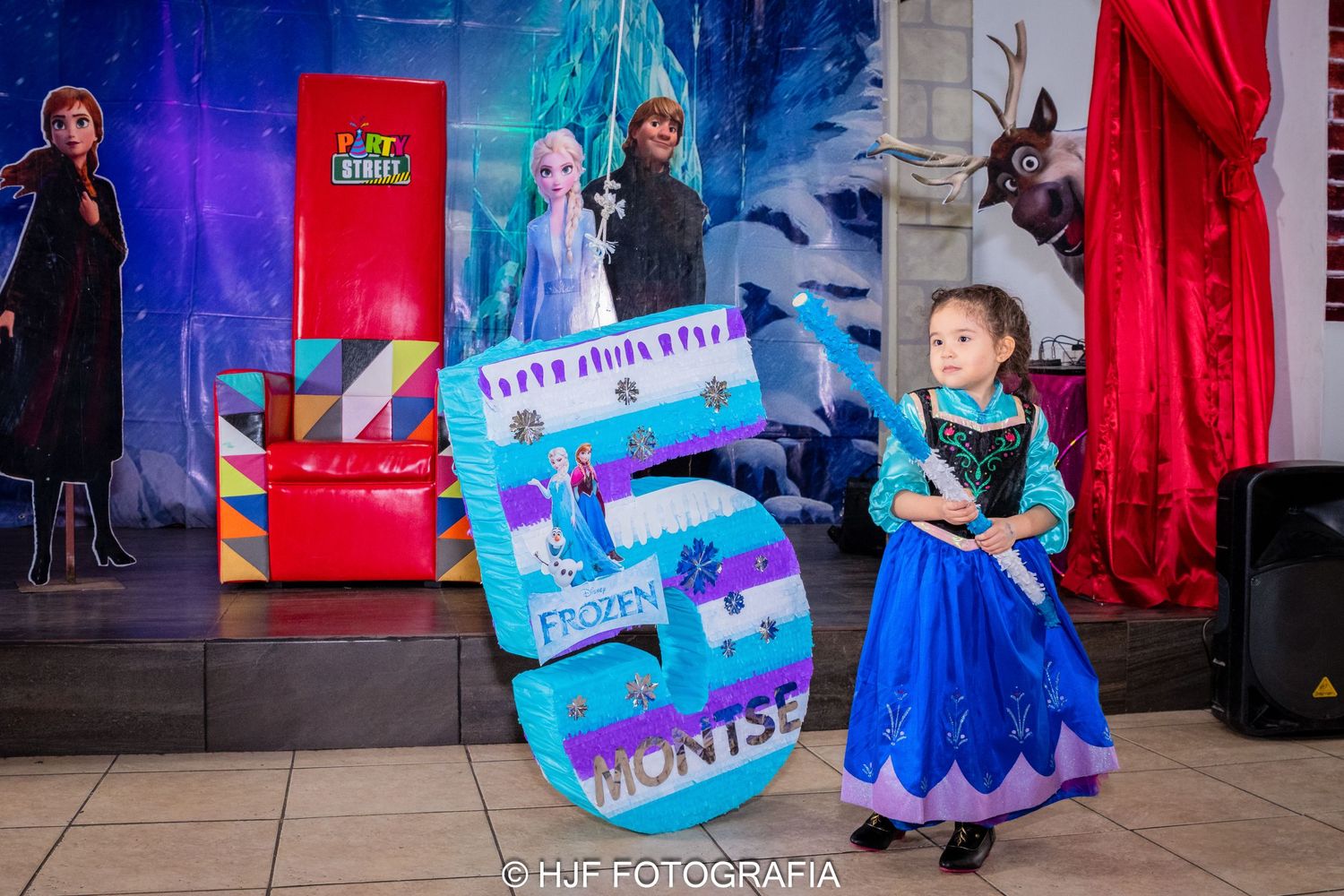Niña feliz rompiendo una piñata durante su fiesta de cumpleaños