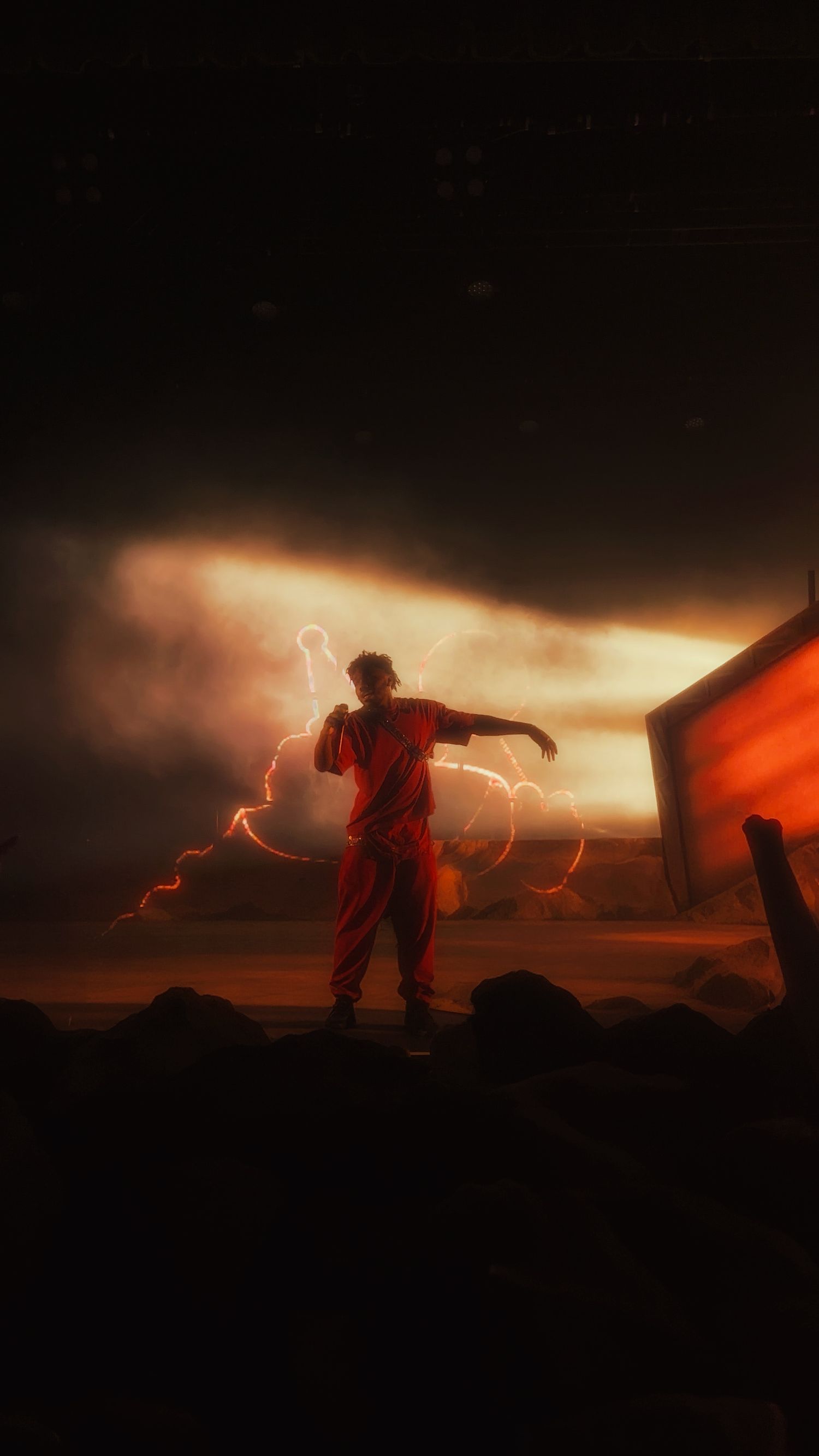 Silhouette of a person in red outfit standing amid lightning bolts in a dramatic dark landscape.