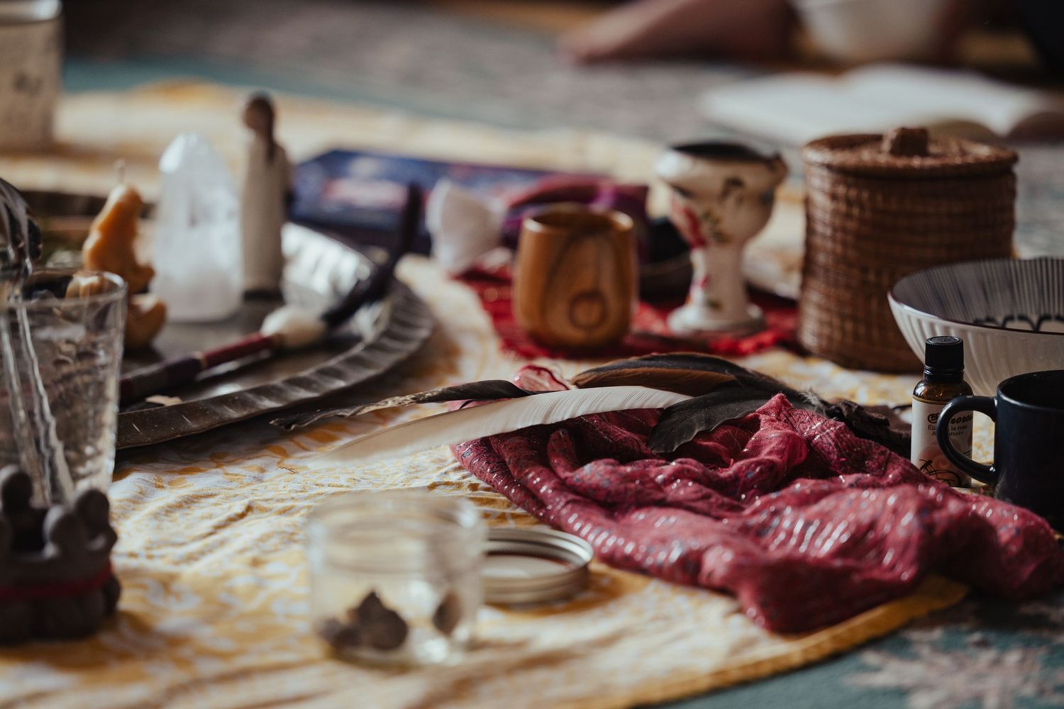 Rustic ceremonial table with crystals, wooden cups, feathers, and ritual objects for a spiritual gathering.