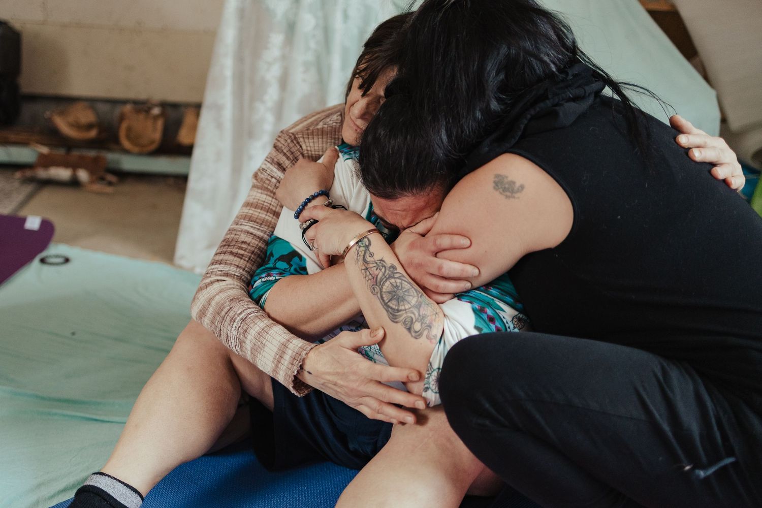 A doula supports a laboring woman in a warm embrace during active labor on a blue birthing ball.