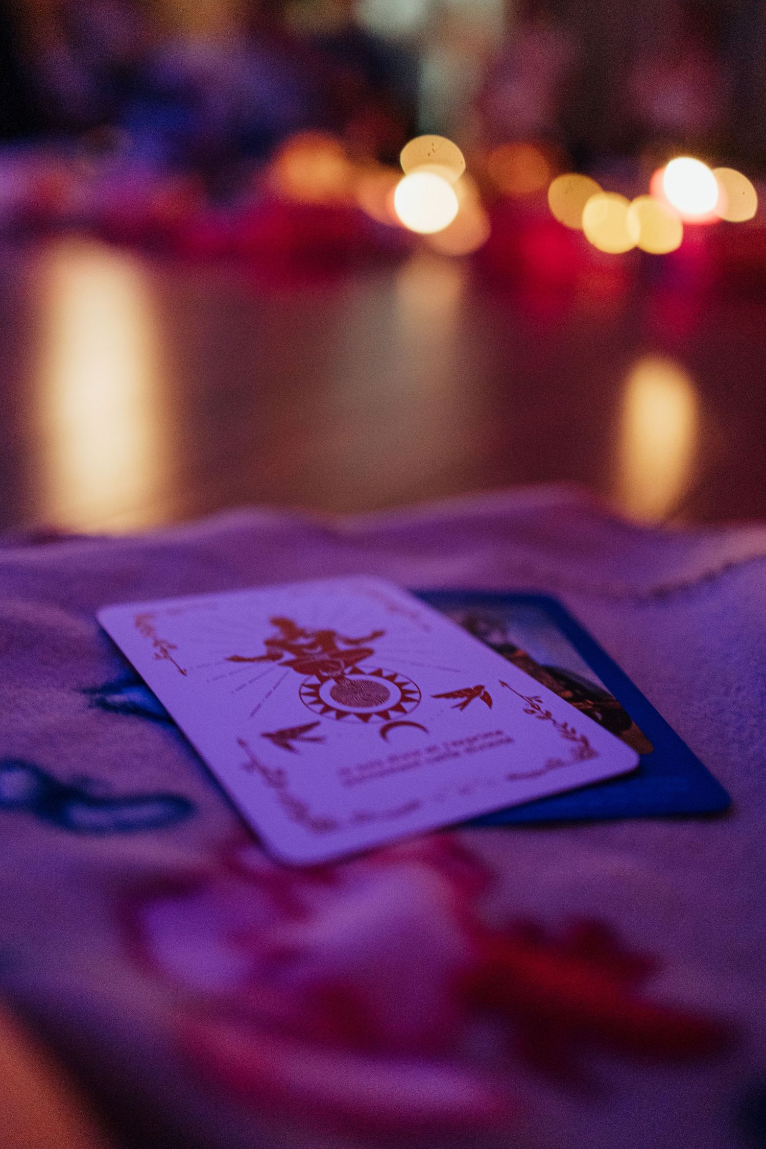 A tarot card rests on purple cloth in candlelight ambiance.