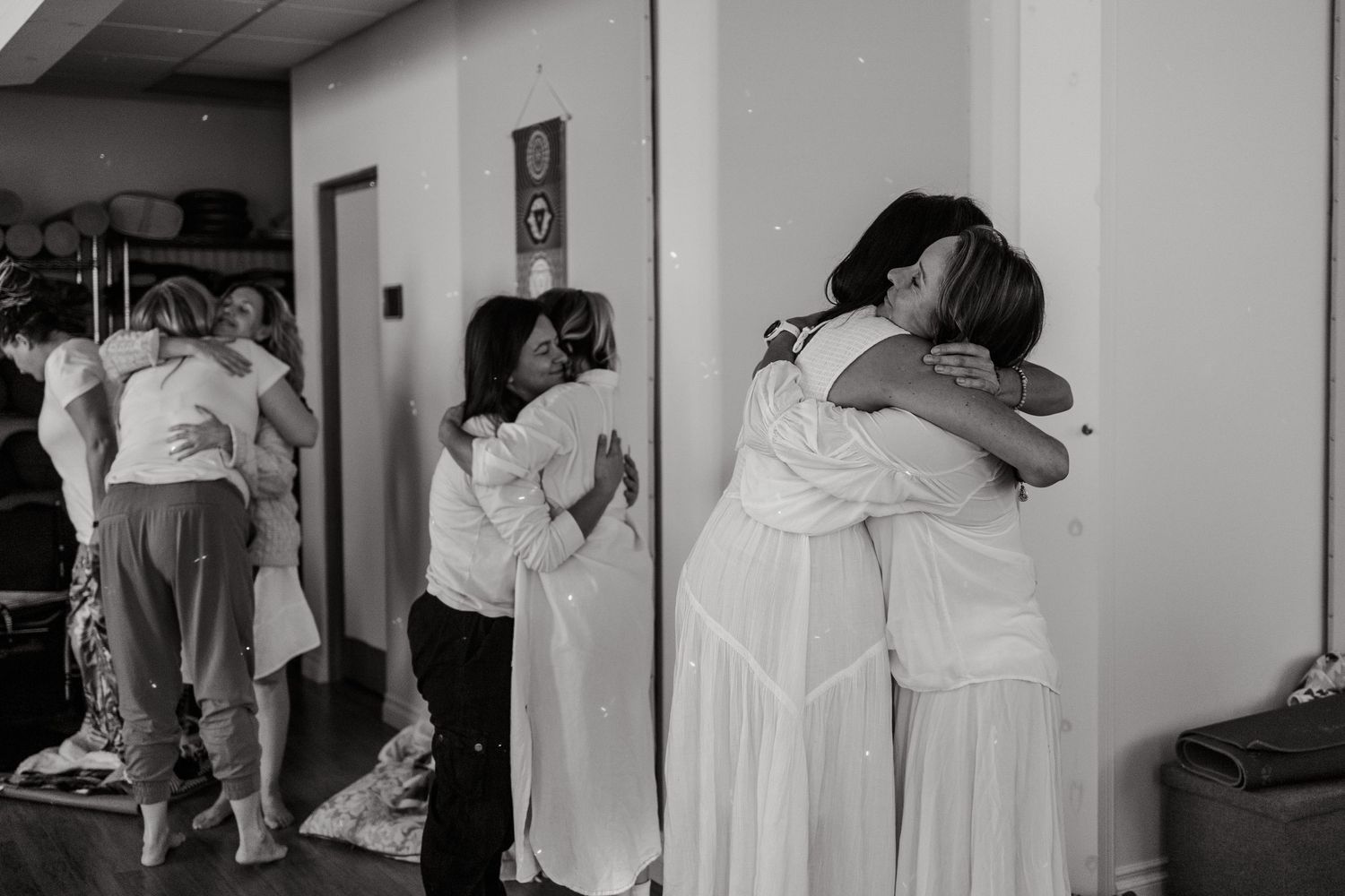 Black and white photo of women hugging in a hallway, capturing an emotional wedding preparation moment.