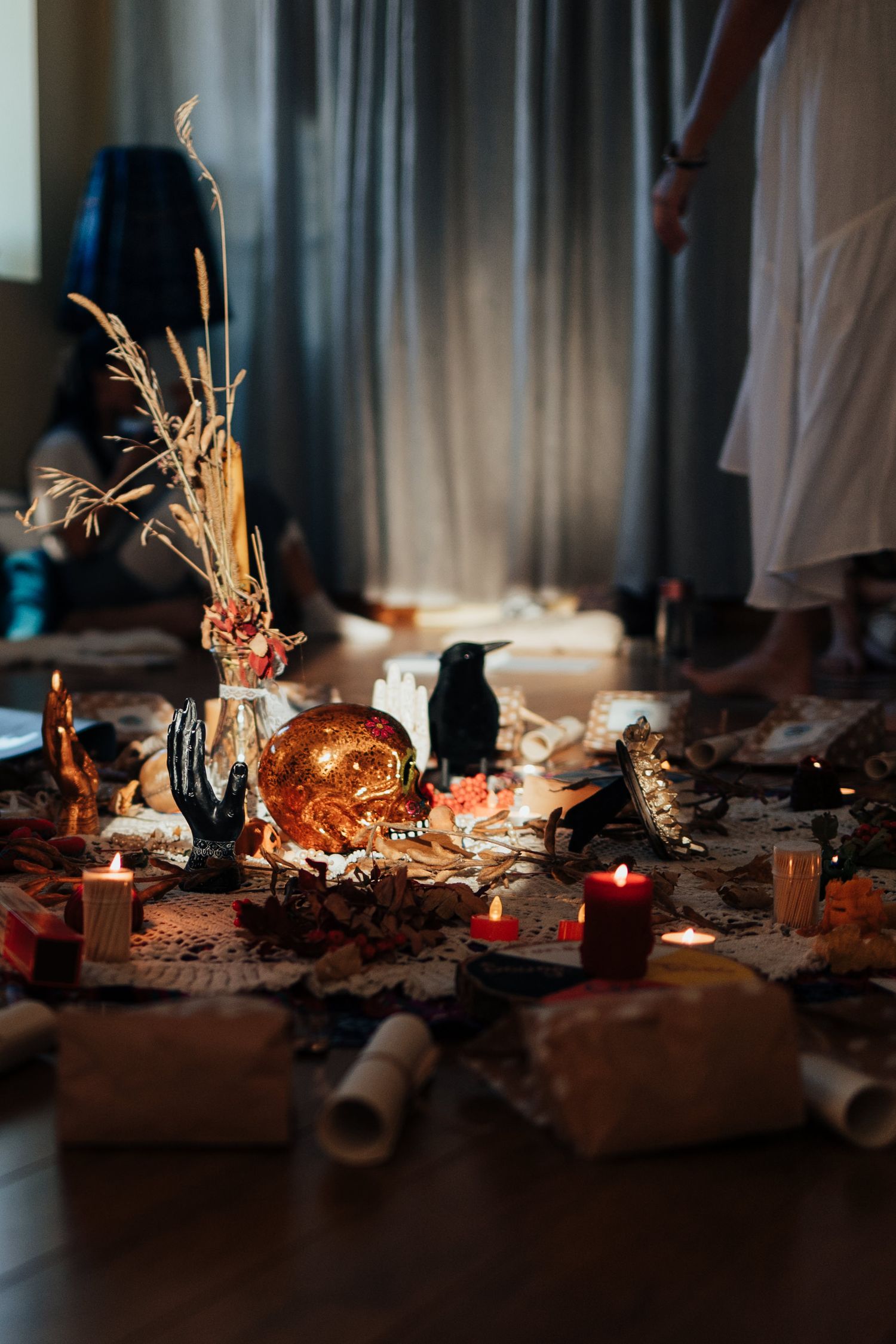 Mystical altar with golden skull, black crow, candles, dried flowers, and scrolls in a dimly lit ritual space.