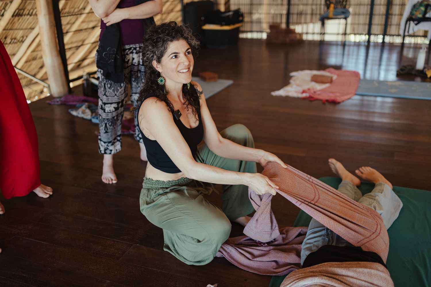 Woman smiling while unpacking a yoga mat in a bright studio during a yoga class.