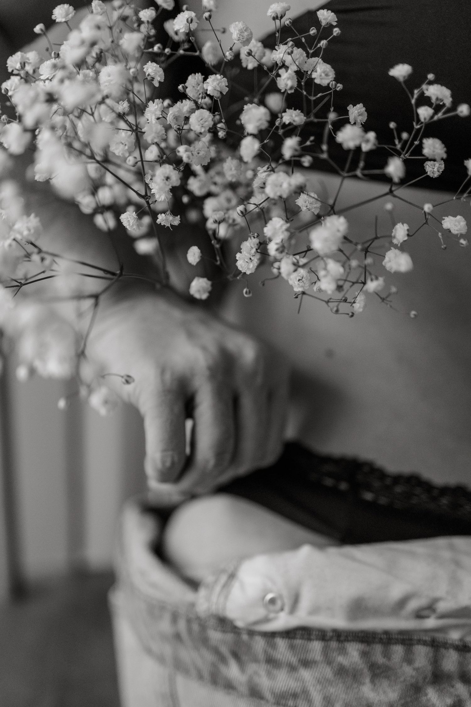 Black and white close-up of hands holding delicate baby's breath flowers.