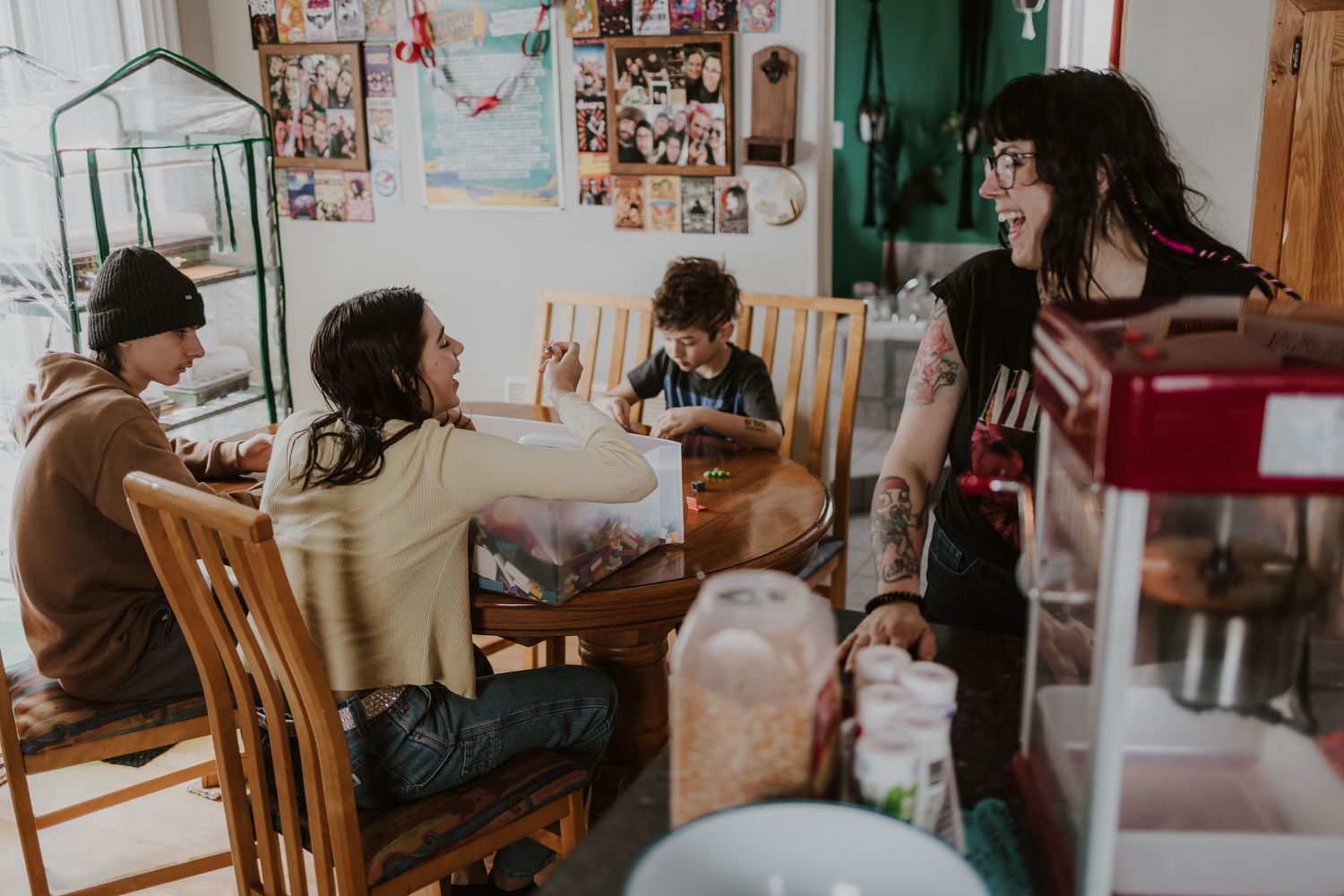 Family gathering around a wooden dining table in a cozy home with photos on the wall.