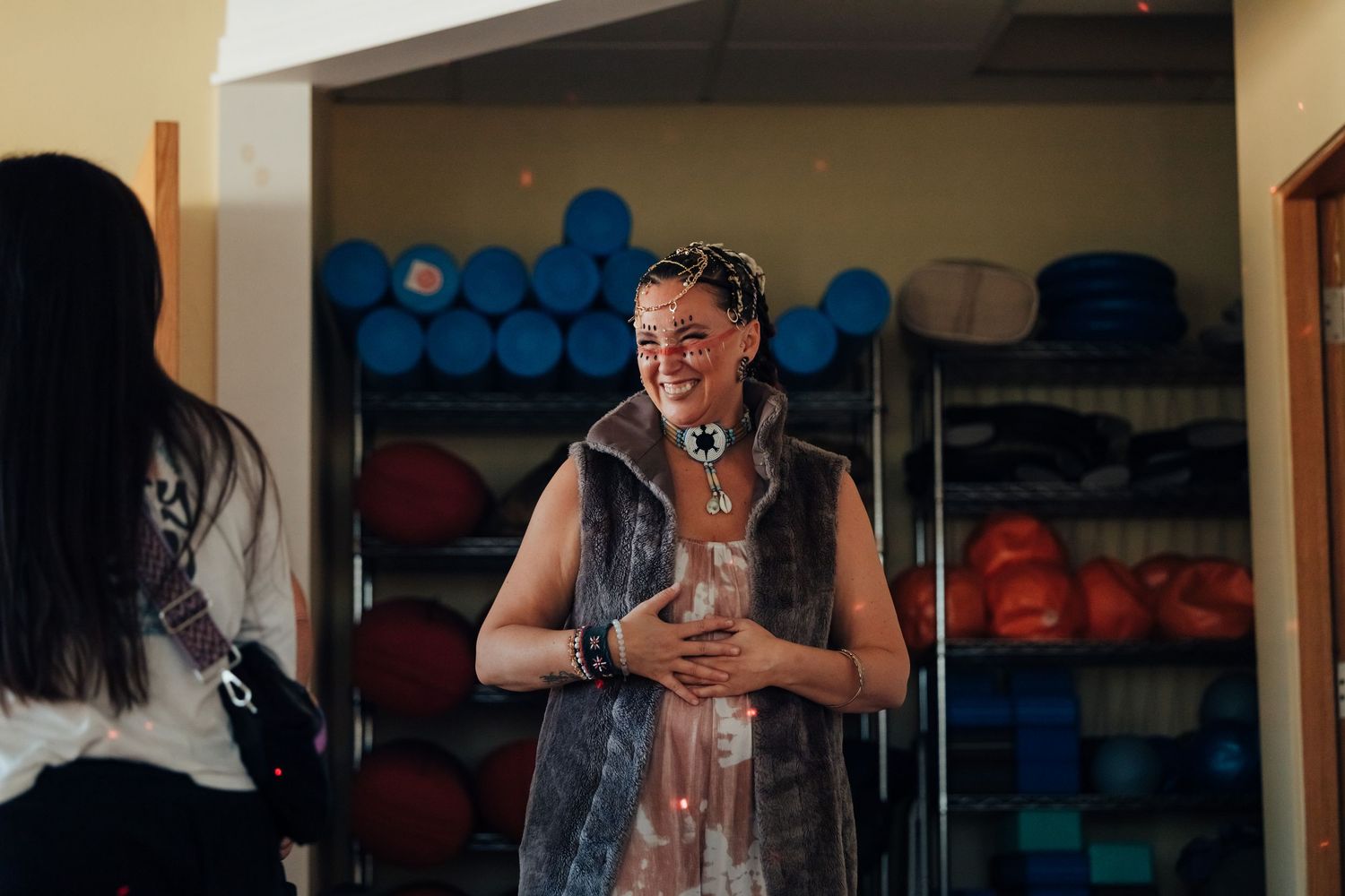 Person covered in slime laughing in a storage room with colorful rolled mats on shelves behind them.