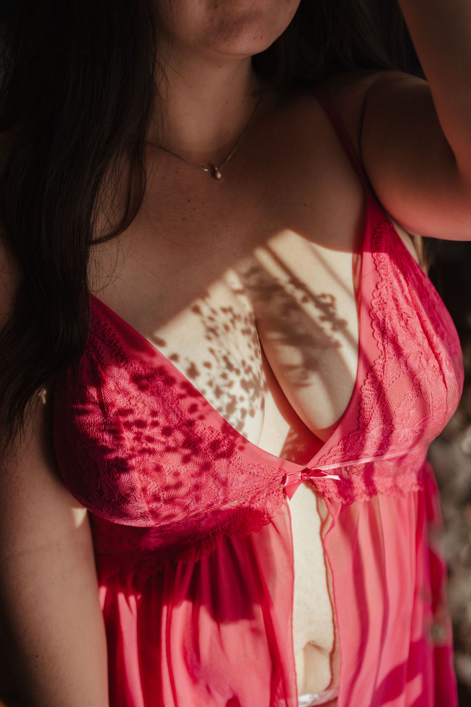 Woman wearing a red lace lingerie babydoll with sheer panels, styled with a delicate gold necklace.