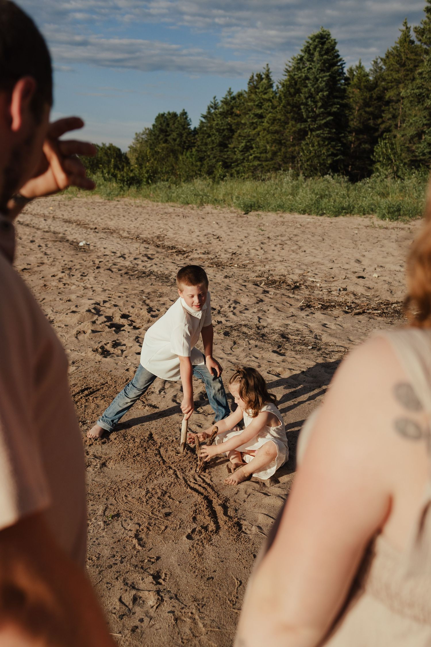 Children playing in the sand on a beach near a forest on a sunny day.