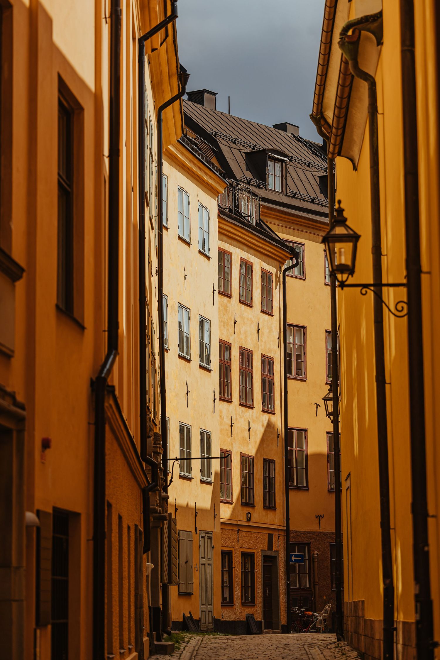 Narrow cobblestone alley flanked by yellow ochre buildings in Stockholm's Gamla Stan old town district.