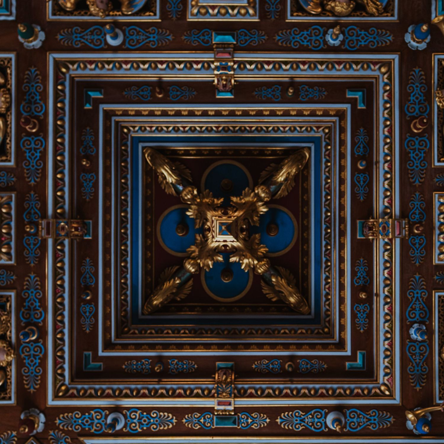 Ornate ceiling with intricate blue and gold geometric patterns, featuring a central medallion with gilded floral motifs.
