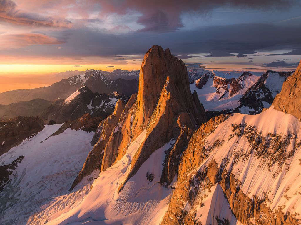 Stunning sunset illuminates the rugged granite spires of Mount Fitz Roy surrounded by snow in Patagonia.