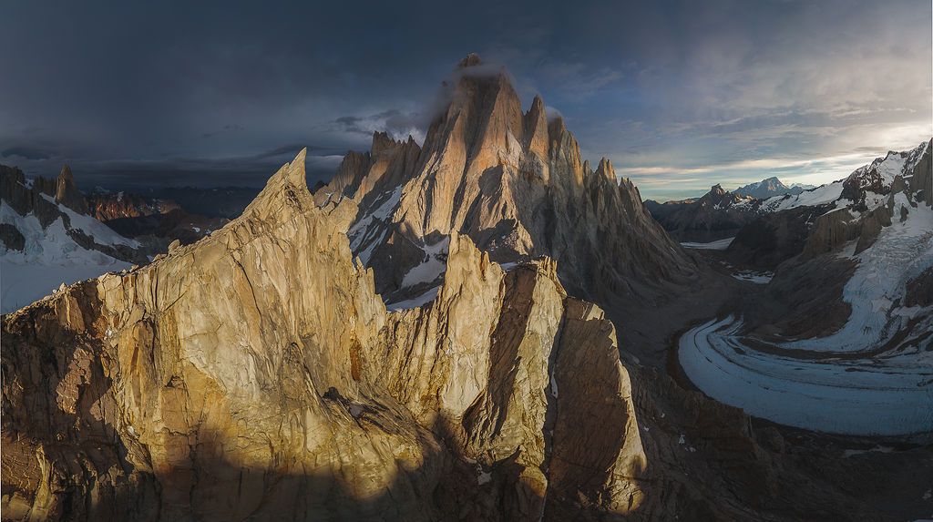 Dramatic aerial sunset view of Patagonia's granite towers with a glacier-carved valley below.