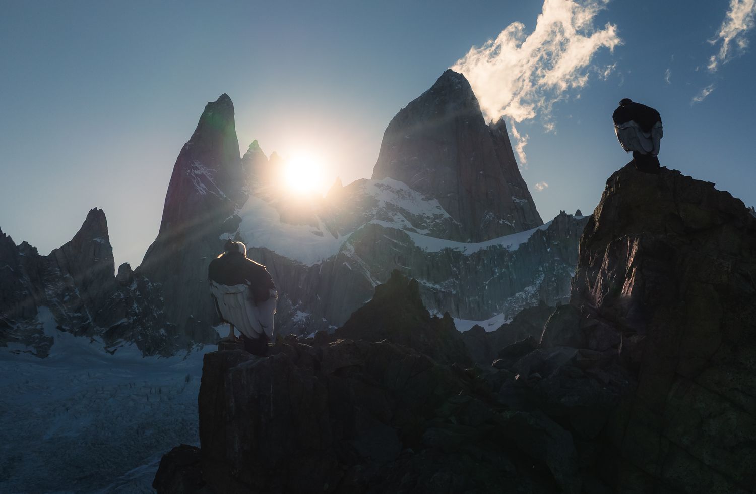 Silhouetted rocky mountain peaks backlit by a golden sunset in a dramatic Patagonian landscape.