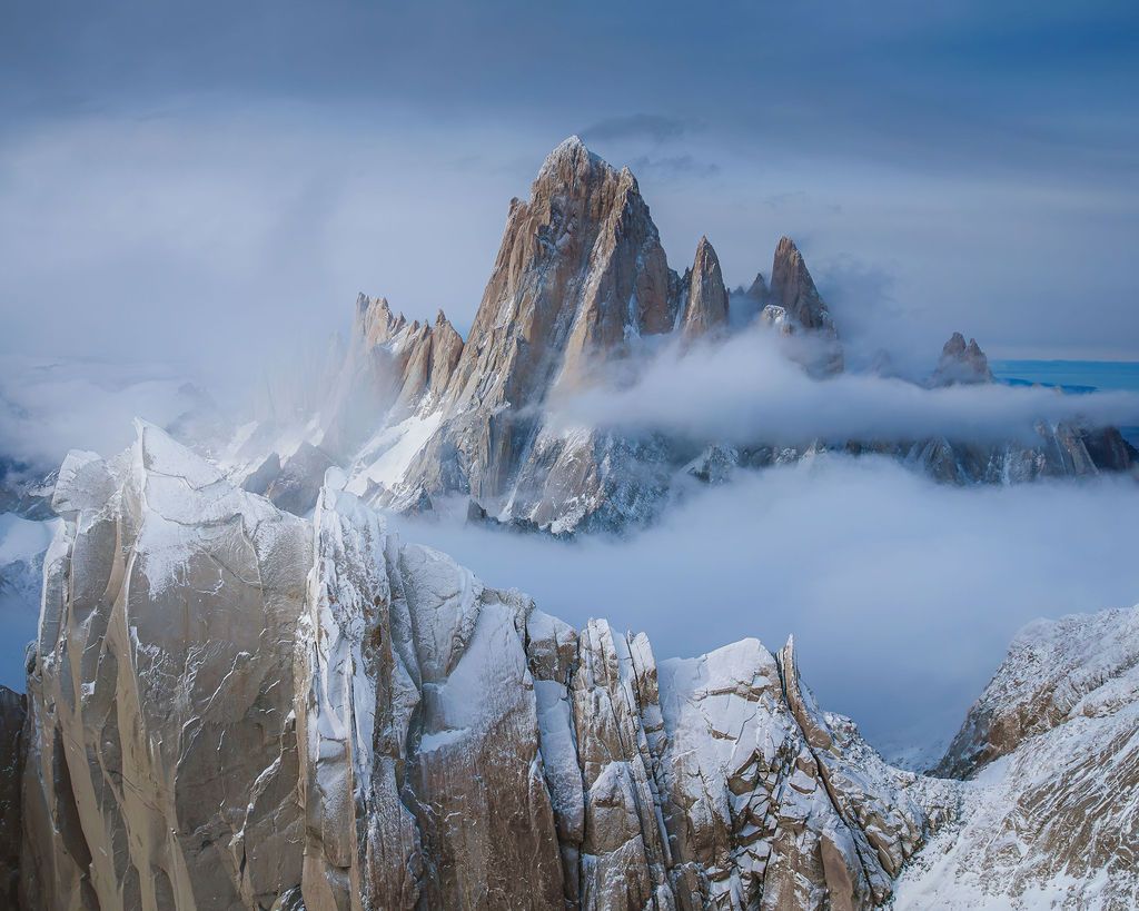 Majestic Mount Fitz Roy emerges dramatically through swirling clouds and mist in Patagonia, Argentina.