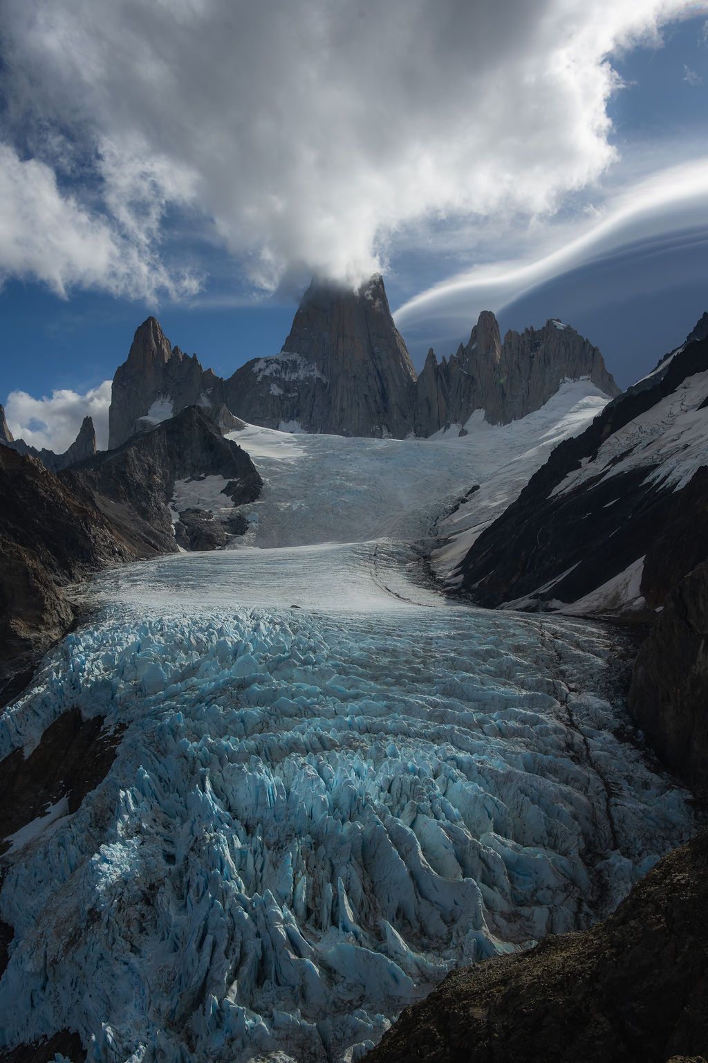 Vast blue glacial ice field stretches toward the jagged peaks of Mount Fitz Roy.