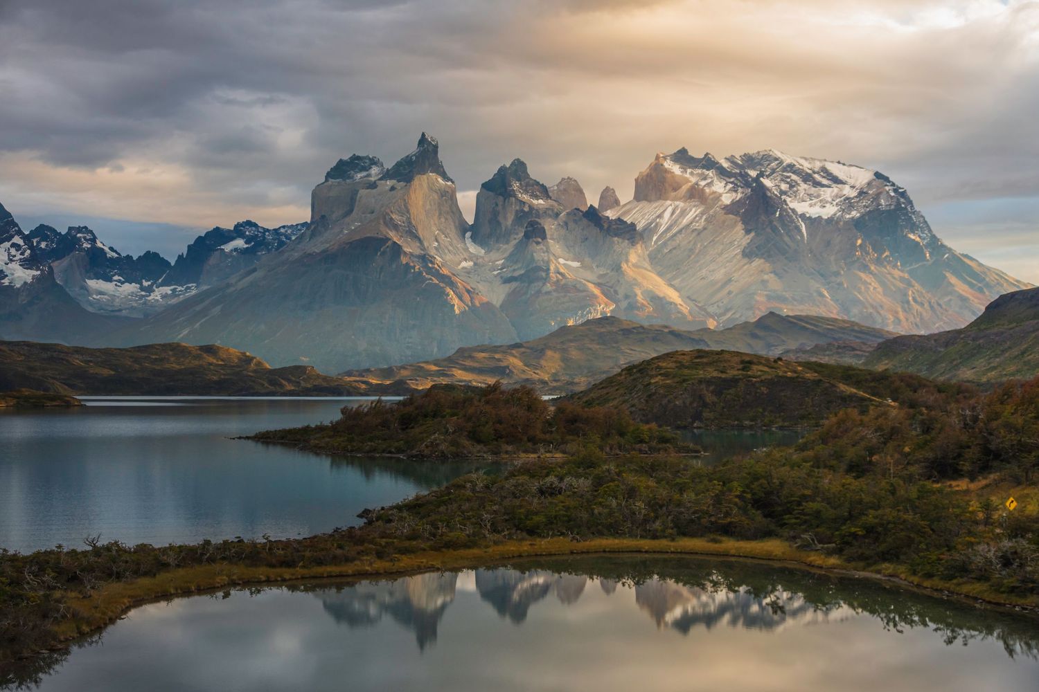 Dramatic mountain landscape reflecting in calm lake waters at Torres del Paine National Park, Patagonia, Chile.