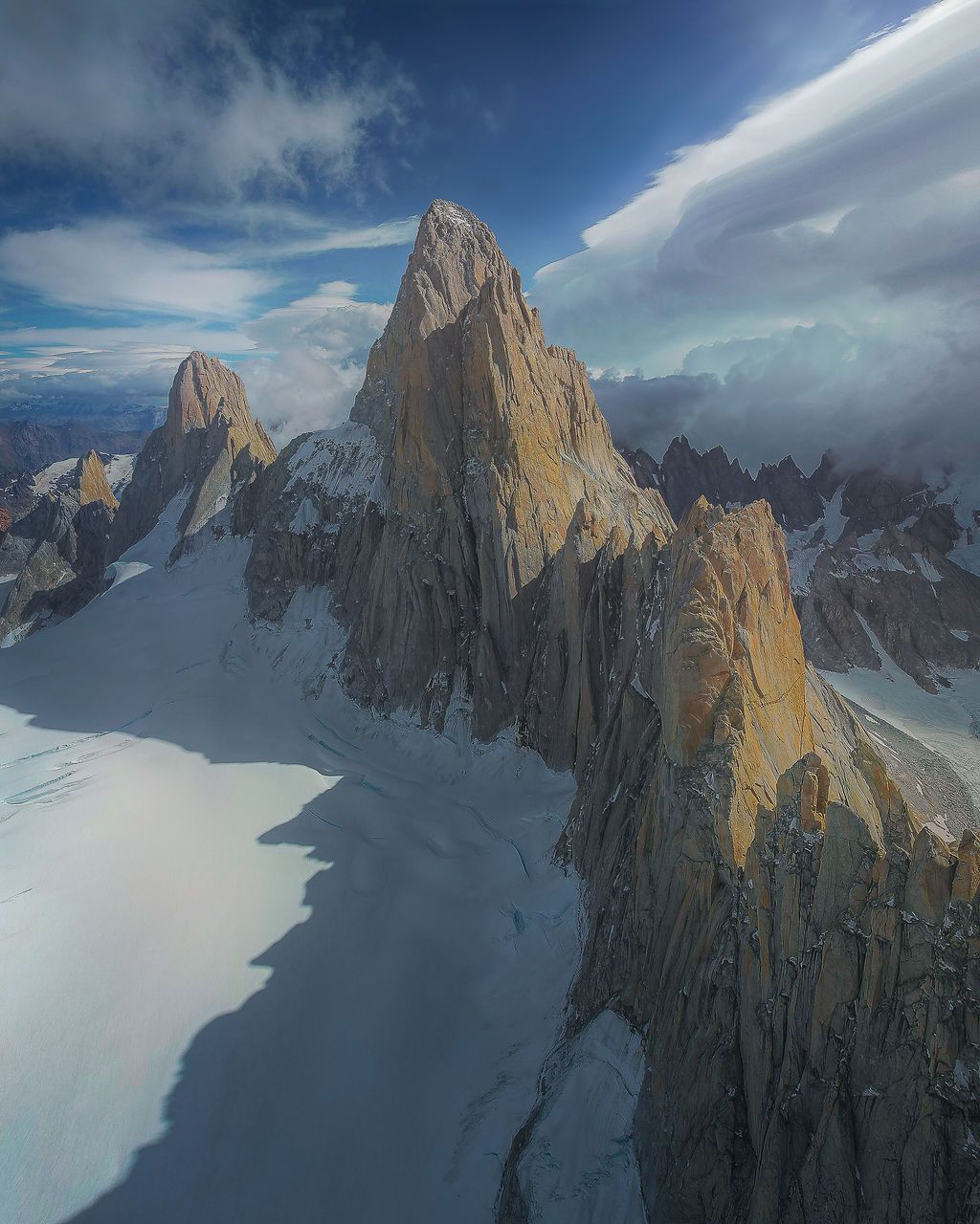 Aerial view of Cerro Torre's sharp granite peaks surrounded by glaciers and dramatic clouds in Patagonia.