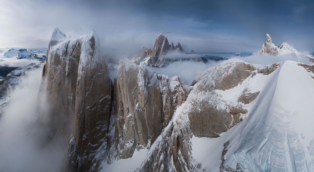 Misty clouds swirl around towering granite spires of the Cerro Torre massif in Patagonia, Argentina.