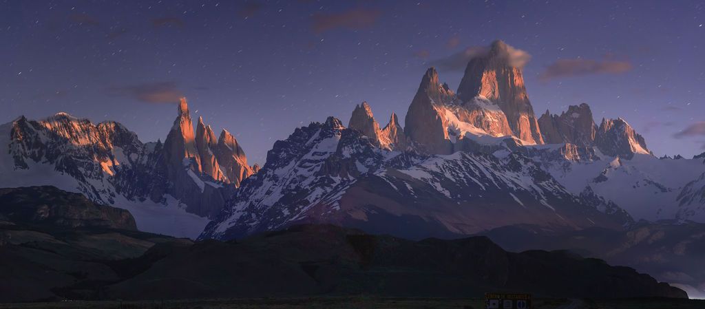 Panoramic twilight view of snow-capped Fitz Roy and Cerro Torre mountain range in Patagonia.