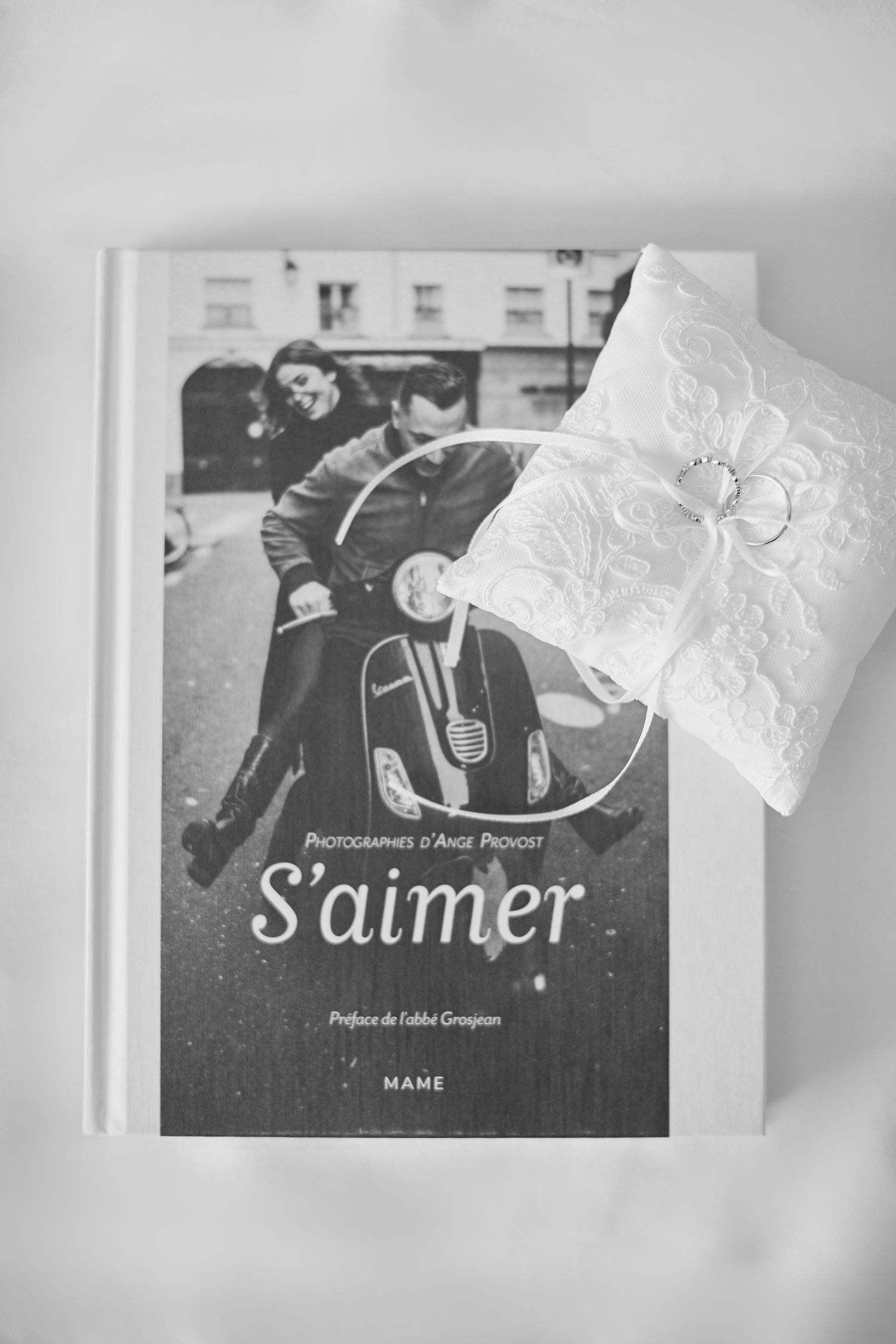 Black and white photo of wedding ring pillow beside a book titled S'aimer by photographer Ange Provost.