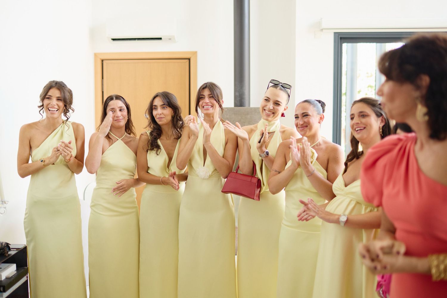 Group of bridesmaids in yellow dresses clapping and smiling during wedding getting ready moment.