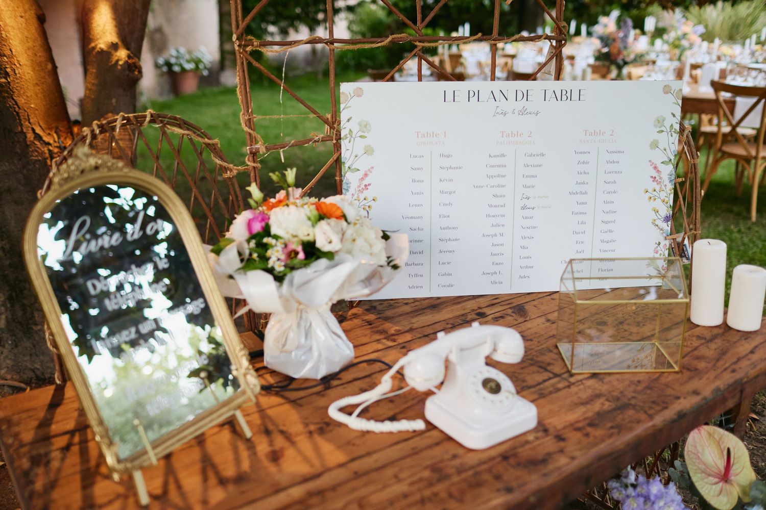 Close-up of wedding welcome table with seating chart, vintage white telephone, mirror sign, and candles.