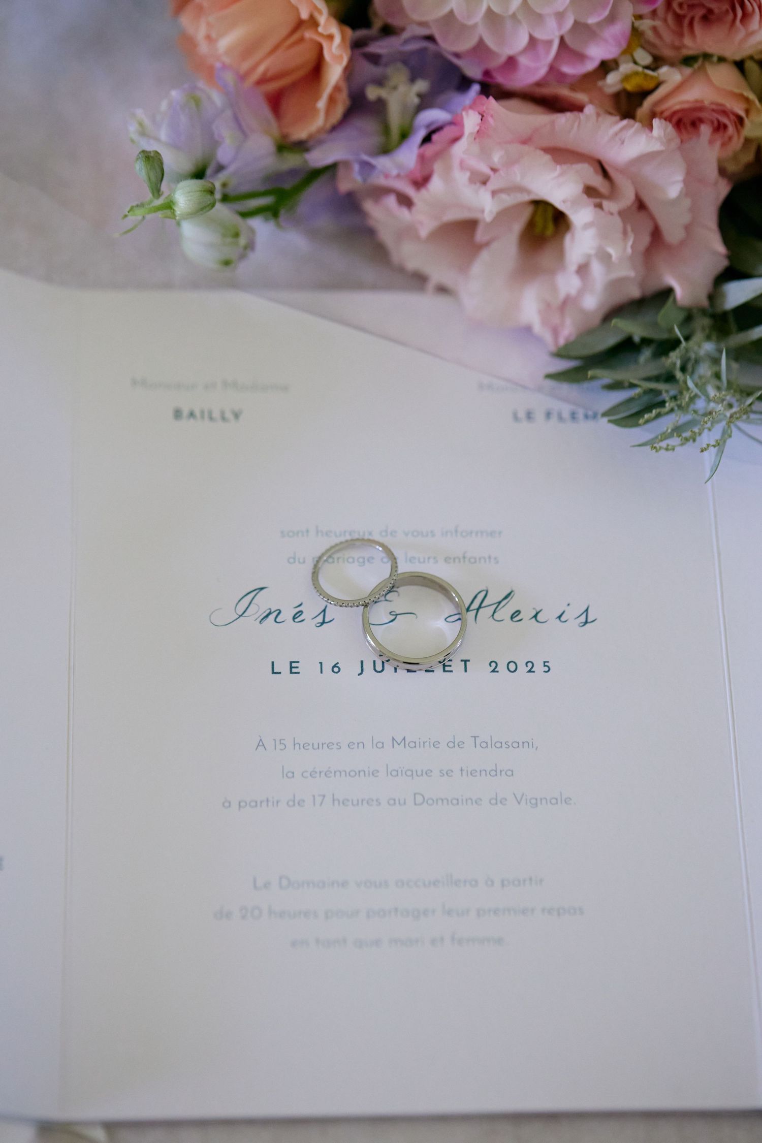 Wedding invitation for Ines and Alexis dated July 16, 2023, with two silver rings and pink flowers.