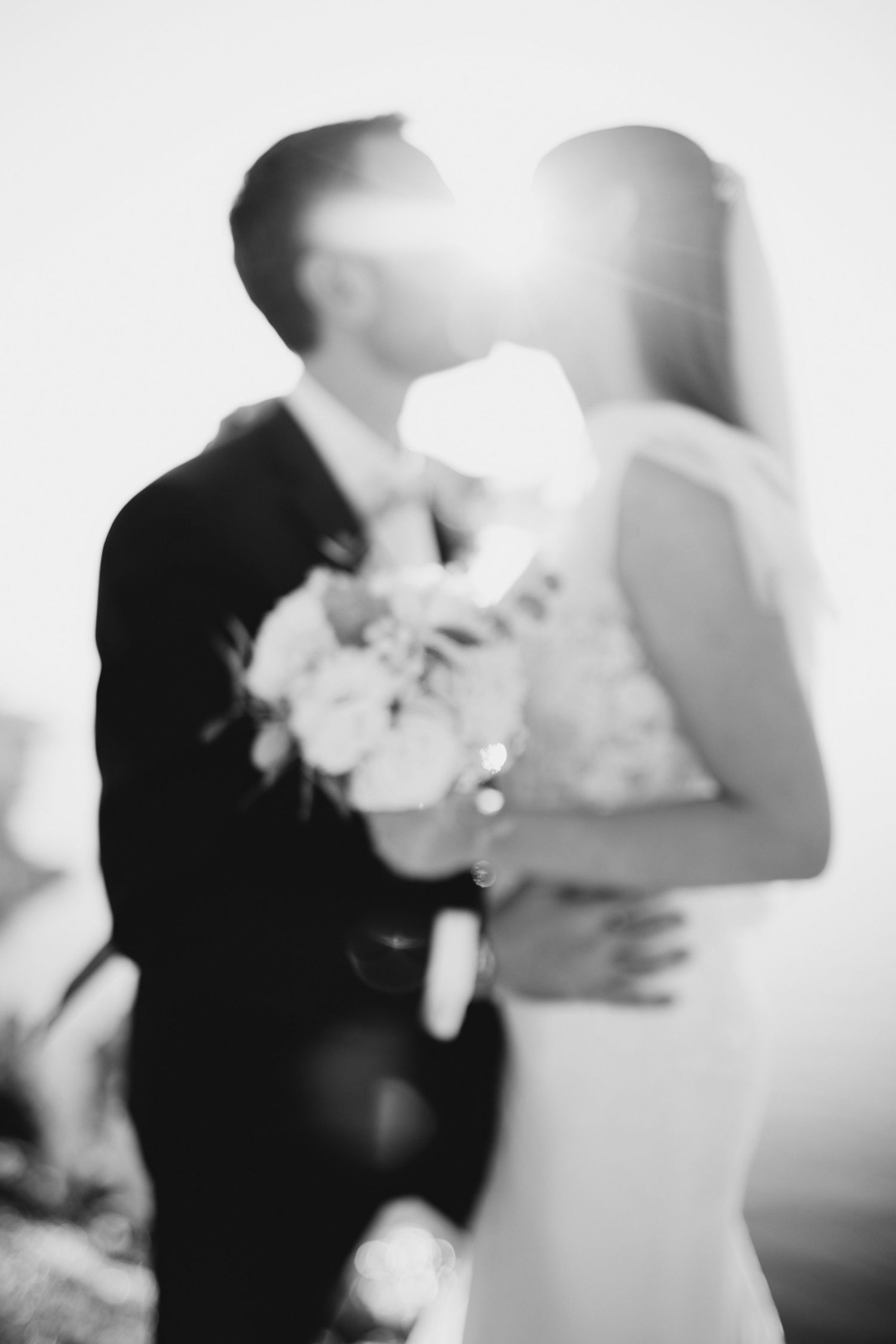 Les mariés s'embrassent dans un portrait en noir et blanc pendant leur mariage.