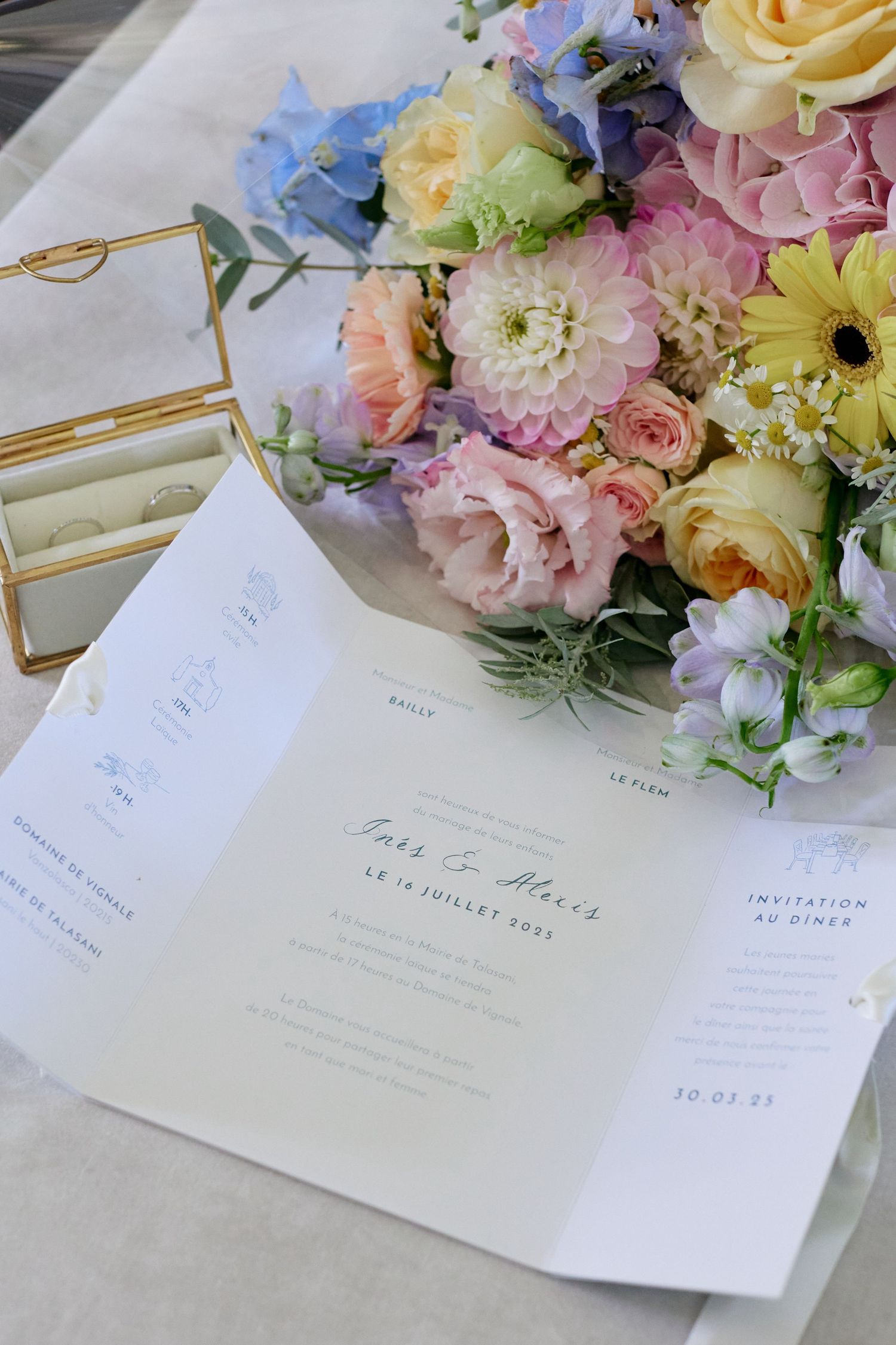 Elegant wedding stationery for Ines and Alexis beside a colorful pastel floral bouquet and ring box.