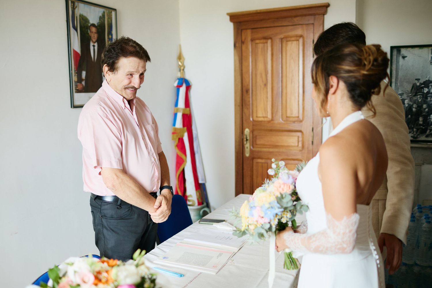Officiant stands with bride holding pastel bouquet during intimate civil wedding ceremony.