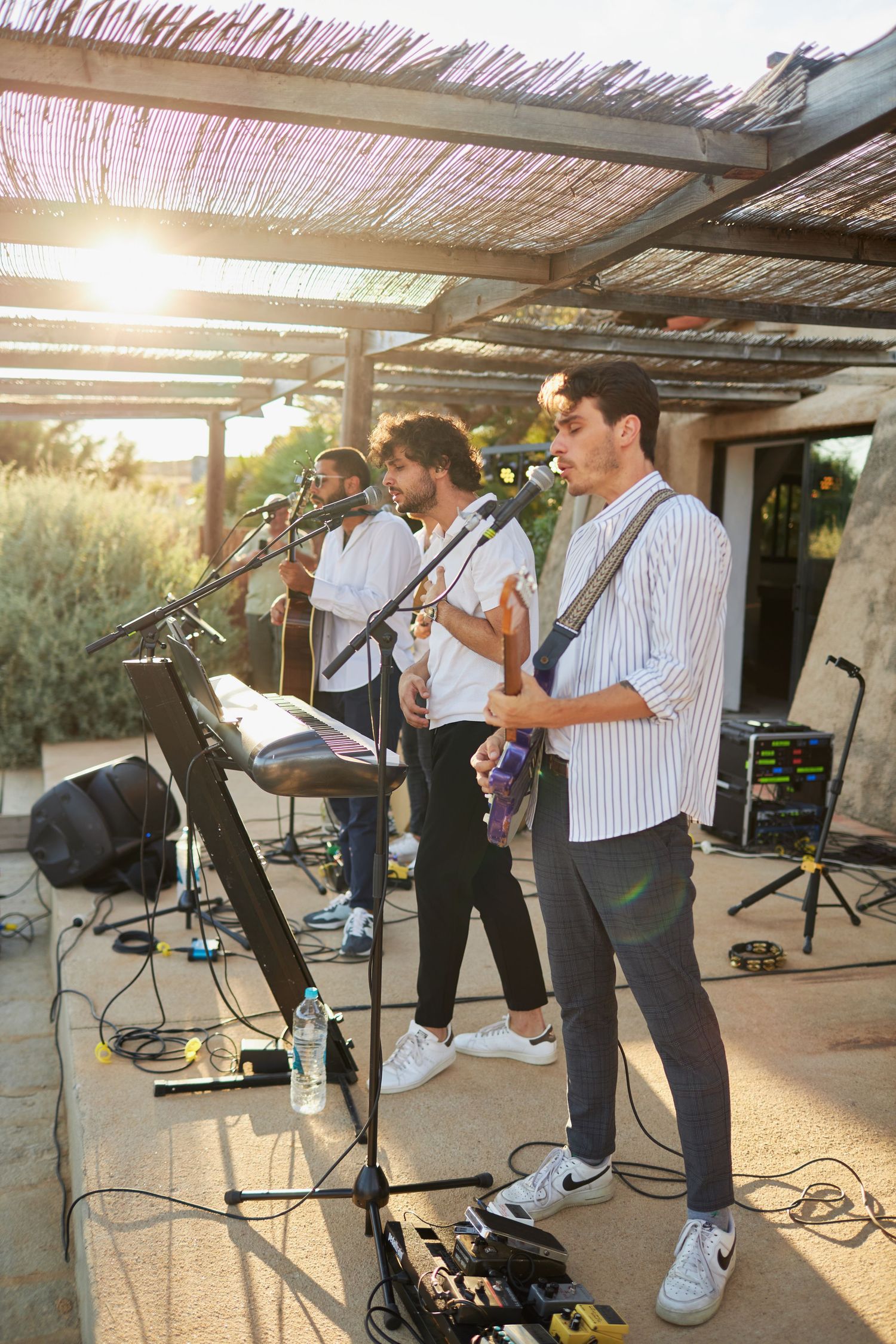 Live band performing at an outdoor wedding reception under a pergola at golden hour.