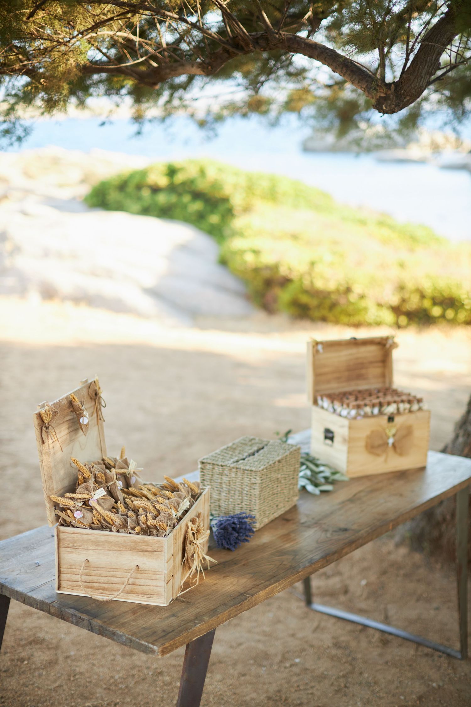 Rustic wooden table with wicker baskets and decorative boxes at a beachside wedding reception.