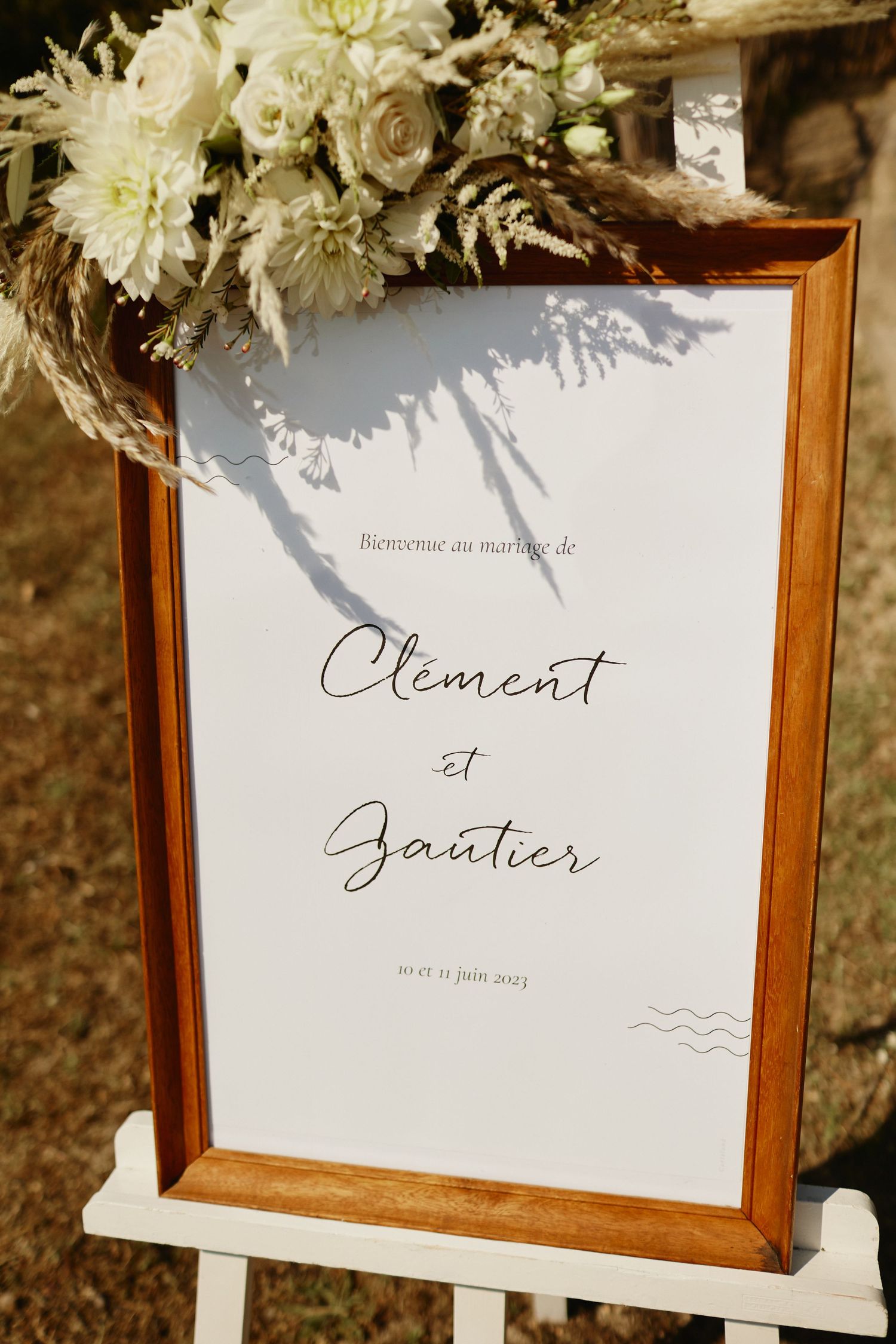 Elegant wooden framed wedding welcome sign for Clement et Gautier with white florals.